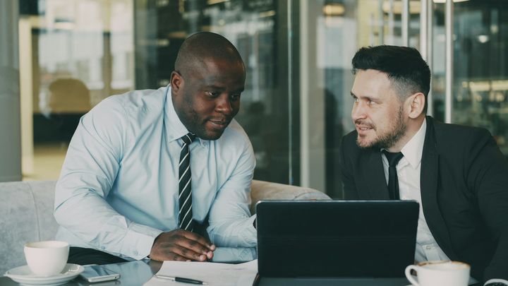 Twee ondernemers in gesprek over belastingzaken achter een laptop